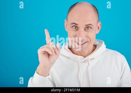 Ritratto di sorridente uomo calvo creativo che ha idea e puntamento verso l'alto con il dito indice Foto Stock