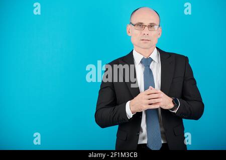 Ritratto di uomo d'affari serio maturo in abito formale e occhiali guardando la macchina fotografica , isolato su blu Foto Stock