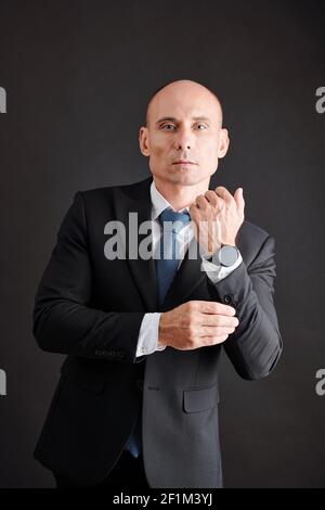 Ritratto di successo serio elegante uomo d'affari tonificante su polsini di la sua giacca Foto Stock