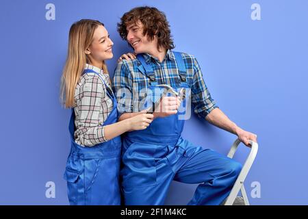 coppia di costruttori capemen, uomo e donna in riparazione uniforme con attrezzi, tenendo in mano il martello per unghie, lavoratori innamorati, lavorare insieme, isolati Foto Stock