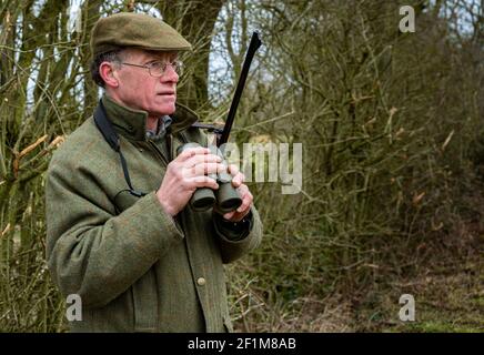 Lincolnshire, Inghilterra, Regno Unito. Un deerstalker finalmente luce guardando e avvistare cervi per l'abbattimento e la gestione come parte di un programma di conservazione Foto Stock