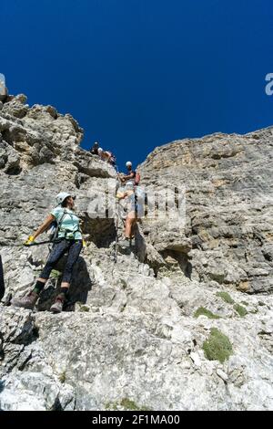 Guida alpina e diversi clienti che salgono su una Via Ferrata in Le Dolomiti Italiane Foto Stock