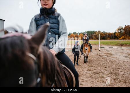 Ragazze che cavalcano pony sul paddock Foto Stock