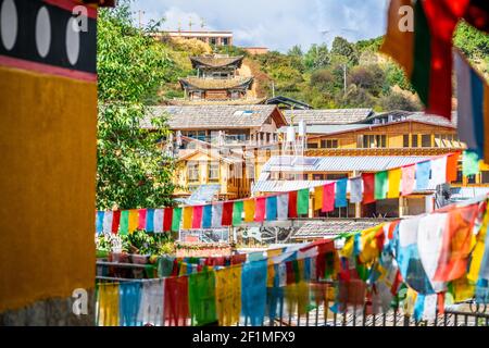 Case e tempio vista tra le bandiere di preghiera nel vecchio Dukezong Città di Shangri-la Yunnan Cina Foto Stock