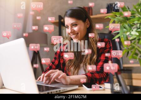 Happy woman chats via laptop con messaggi di social network, chat e icone utente Foto Stock