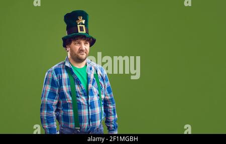 L'uomo con le decorazioni a pentola in cappelli Leprechaun è isolato su una copia verde sfondo dello spazio Foto Stock
