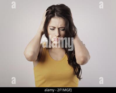 Stressato donna informale infelice con mal di testa orecchie chiuse le mani perché non vuole sentire alcun suono e rumore. Ritratto di primo piano Foto Stock