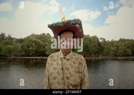 Isola di Rote, Indonesia. 16 luglio 2009. Un abitante che indossa il cappello tradizionale dell'isola di Rote (ti'i langga) in posa per una foto sullo sfondo del lago Peto nel villaggio di Maubesi, dopo aver partecipato a un evento cerimoniale per liberare le tartarughe endemiche del collo di serpente (Chelodina mccordi) allevate in cattività di ritorno al lago, uno degli habitat adatti della specie. Gli abitanti del villaggio hanno raggiunto un consenso per aiutare gli sforzi di conservazione per salvare le specie di tartaruga. Lago Pato, villaggio di Maubesi, rote Ndao regency, Nusa Tenggara Est, Indonesia. Foto Stock