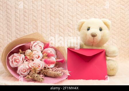 Orsacchiotto polare giocattolo imbottito con fiori e busta rossa con Complimenti. Il concetto di una vacanza per bambini, mamme giorno, compleanno Foto Stock