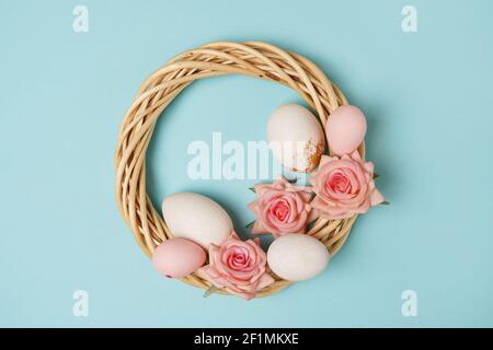 Corona di Pasqua con uova di pasqua e fiori su sfondo blu Foto Stock