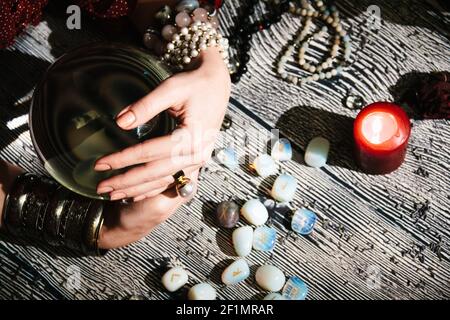 Le mani di Fortuneteller su un orb di vetro. Previsione del futuro. Interno Mystic. Simboli occulti Foto Stock