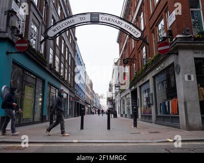 Empty and Quiet Carnaby Street London UK, during the coronavirus, covid-19, Lockdown in England, UK, con i lavoratori che camminano davanti indossando le maschere ppe Foto Stock