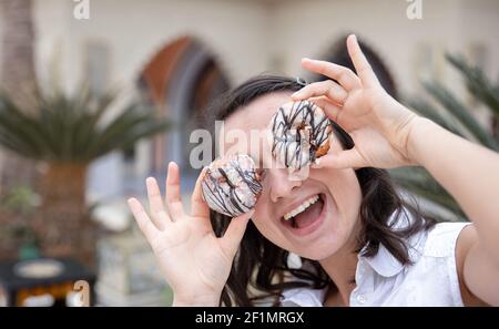 Ragazza divertente in posa con le ciambelle in estate all'aperto. Concetto di vacanza. Foto Stock