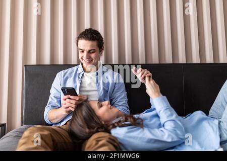 Arrabbiato giovane ognuno con i propri cellulari sdraiato sul letto di casa Foto Stock