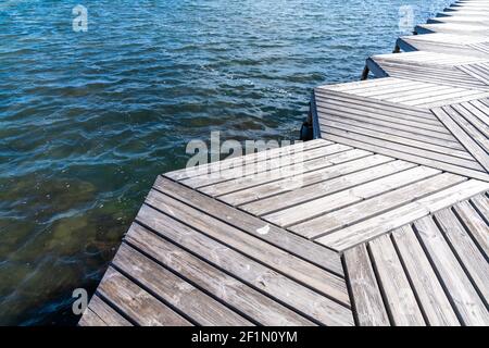 Un primo piano basso angolo astratto vista di un legno passerella e molo che conducono all'oceano Foto Stock