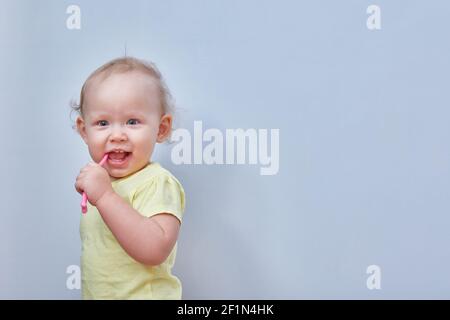 Il bimbo pennellerà i denti su uno sfondo chiaro. Spazio di copia. Foto Stock