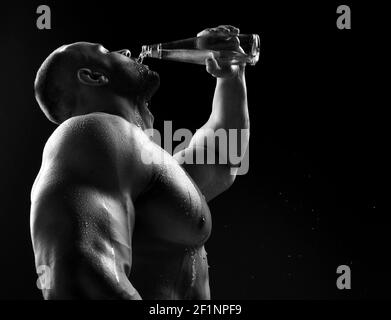 Giovane muscoloso costruire uomo silhouette bere acqua dalla bottiglia dopo la corsa o dopo l'allenamento all'aperto, fitness Foto Stock