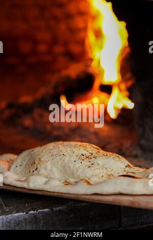 Primo piano su un pitta pane fresco con sesamo semi che escono da un forno a legna Foto Stock