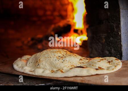 Primo piano su un pitta pane fresco con sesamo semi che escono da un forno a legna Foto Stock