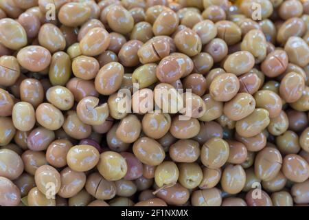 Olive verdi accatastate su una superficie come sfondo Foto Stock