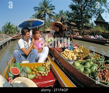 Thailandia. Bangkok. Mercato galleggiante. Turisti con venditore di frutta. Foto Stock