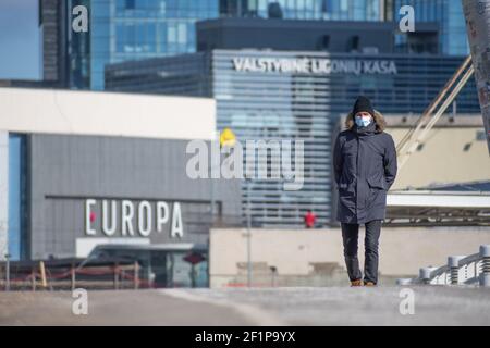 Uomo o ragazzo con maschera e cappuccio di ushanka o pelliccia Passeggiate nel centro della città durante l'epidemia di Covid o Coronavirus Foto Stock