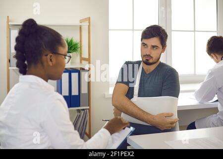 Il paziente con la mano nel punto di imbracatura per bendaggio al gomito ferito su appuntamento con il medico Foto Stock