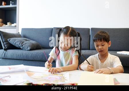 Talento creativo fratello vietnamita e sorella godendo di disegno insieme Foto Stock