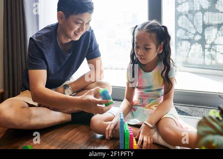 Padre e figlia trascorrono il tempo insieme e costruiscono passi con blocchi in plastica Foto Stock