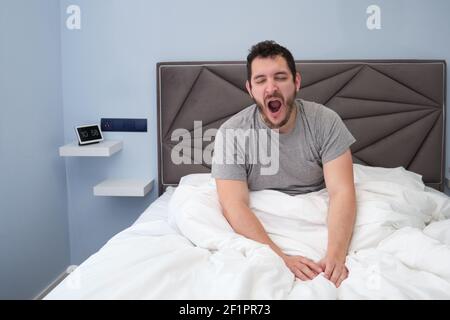 Giovane latino che urla a letto dopo aver dormito. Tarda mattinata. Foto Stock