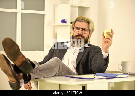 Concetto di crisi. Uomo di successo imprenditore formale di affari seduta ufficio interno. Il manager aziendale si rilassa. Lavoro in ufficio. Concetto aziendale. Hipster giocare palla da tennis. Burnout e mancanza di idee. Foto Stock