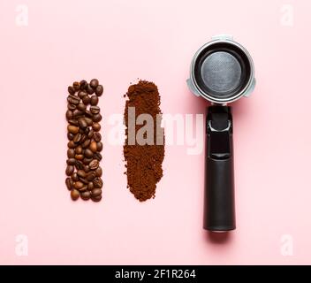 Portafiltro per macchina espresso, caffè macinato e chicchi di caffè su sfondo rosa. Foto Stock