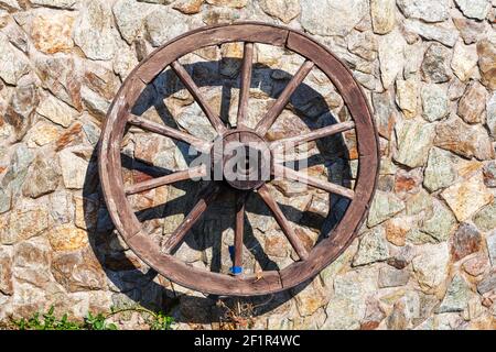 Ruota del carro . Ruota a cardano in legno come un arredamento sulla parete. Finitura in legno bruciato . Buono per uso ornamentale come caratteristica rustica Foto Stock