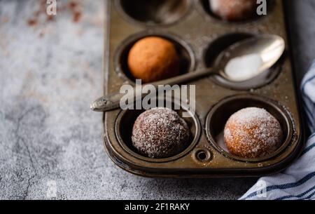 Primo piano di ciambelle ricoperte di zucchero in una teglia da forno. Foto Stock