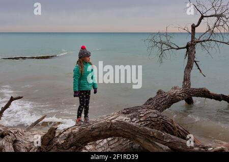 Vista laterale di un bambino che cammina sul lungolago in freddo meteo Foto Stock