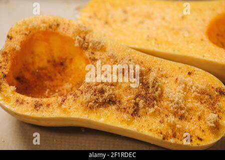 La zucca di butternut è stata dimezzata e ricoperta di zucchero di canna prima della cottura Foto Stock