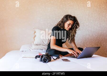 Stock foto di felice ragazza che lavora con il computer nel letto e mangiare frutta. Foto Stock