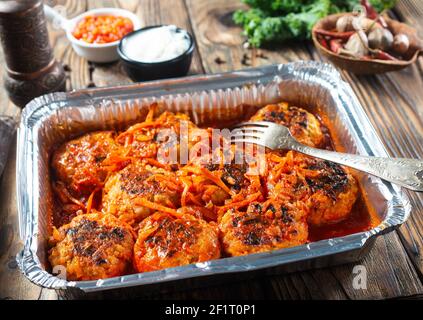 Polpette in salsa di pomodoro cotte in un contenitore di alluminio. Foto Stock