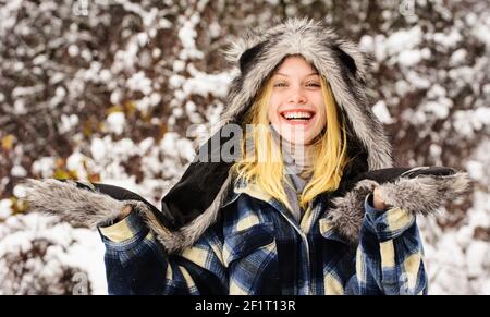 Moda ragazza in inverno. Bella donna in abiti caldi nel parco invernale. Donna felice in cappotto caldo, cappello di pelliccia e mittens. Foto Stock