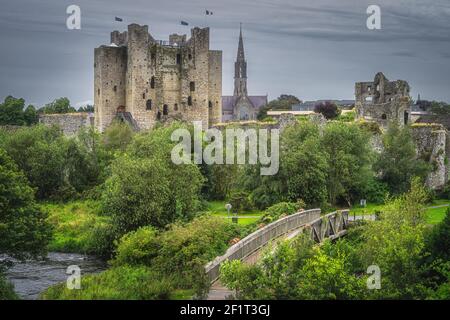 Ponte di legno sul fiume Boyne con vista sul castello di Trim in rovina e la chiesa di St Patricks sullo sfondo nel villaggio di Trim, County Meath, Irlanda Foto Stock