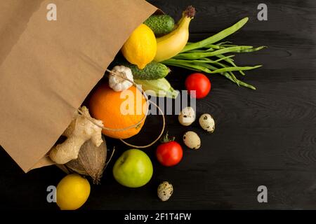 Sacchetto di carta con verdure e frutta sullo sfondo nero di legno. Concetto di cibo in sacchetto. Vista dall'alto.Copia spazio. Foto Stock