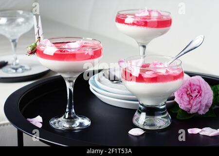 Dessert di panna cotta alla vaniglia con petali di rosa. Foto Stock