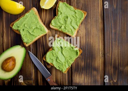 Panini vegetariani con avocado sullo sfondo di legno marrone.Vista dall'alto.spazio fotocopie. Foto Stock
