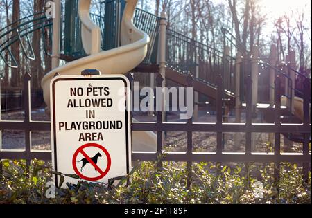 Animali domestici non ammessi nell'area del parco giochi Accedi di fronte alle recinzioni in un parco giochi recintato di un quartiere residenziale suburbano. Gli animali domestici possono causare zone urbane Foto Stock