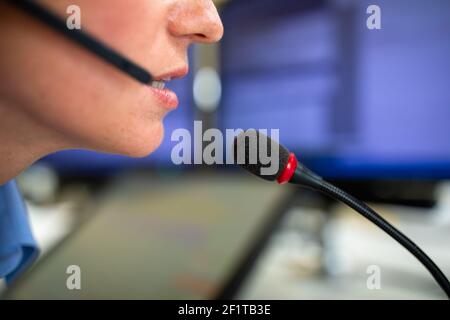 Il dipendente del call center comunica tramite telefono utilizzando un microfono esterno per una migliore ergonomia e sounf Foto Stock