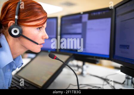 Il dipendente del call center comunica tramite telefono utilizzando un microfono esterno per una migliore ergonomia e sounf Foto Stock