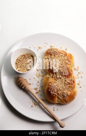 Cucina rumena. Mucenici fatti in casa, dolci tradizionali fatti nella figura 8, cosparsi di miele e noci tritate isolate su sfondo bianco. Foto Stock