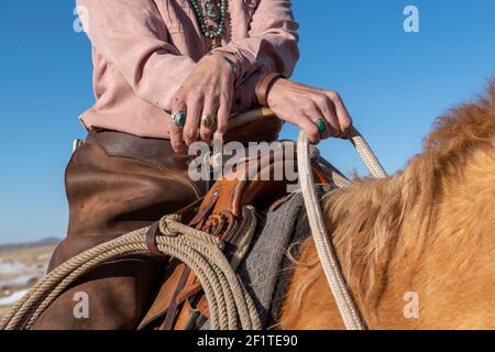 USA, Colorado, Custer County, Westcliffe, Music Meadows Ranch. Particolare della mano femminile ranch in tipico abbigliamento Western ranch e gioielli turchesi. Foto Stock