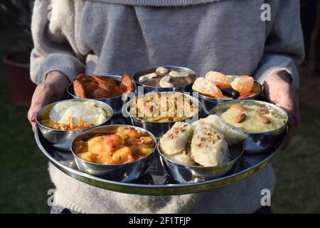 Piatti tradizionali indiani Farali serviti in thali e bocce con molti oggetti per upawas upawas o vrat ka khana. Decorato con petali di fiori per il digiuno Foto Stock