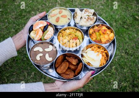 Piatti tradizionali indiani Farali serviti in thali e bocce con molti oggetti per upawas upawas o vrat ka khana. Decorato con petali di fiori per il digiuno Foto Stock